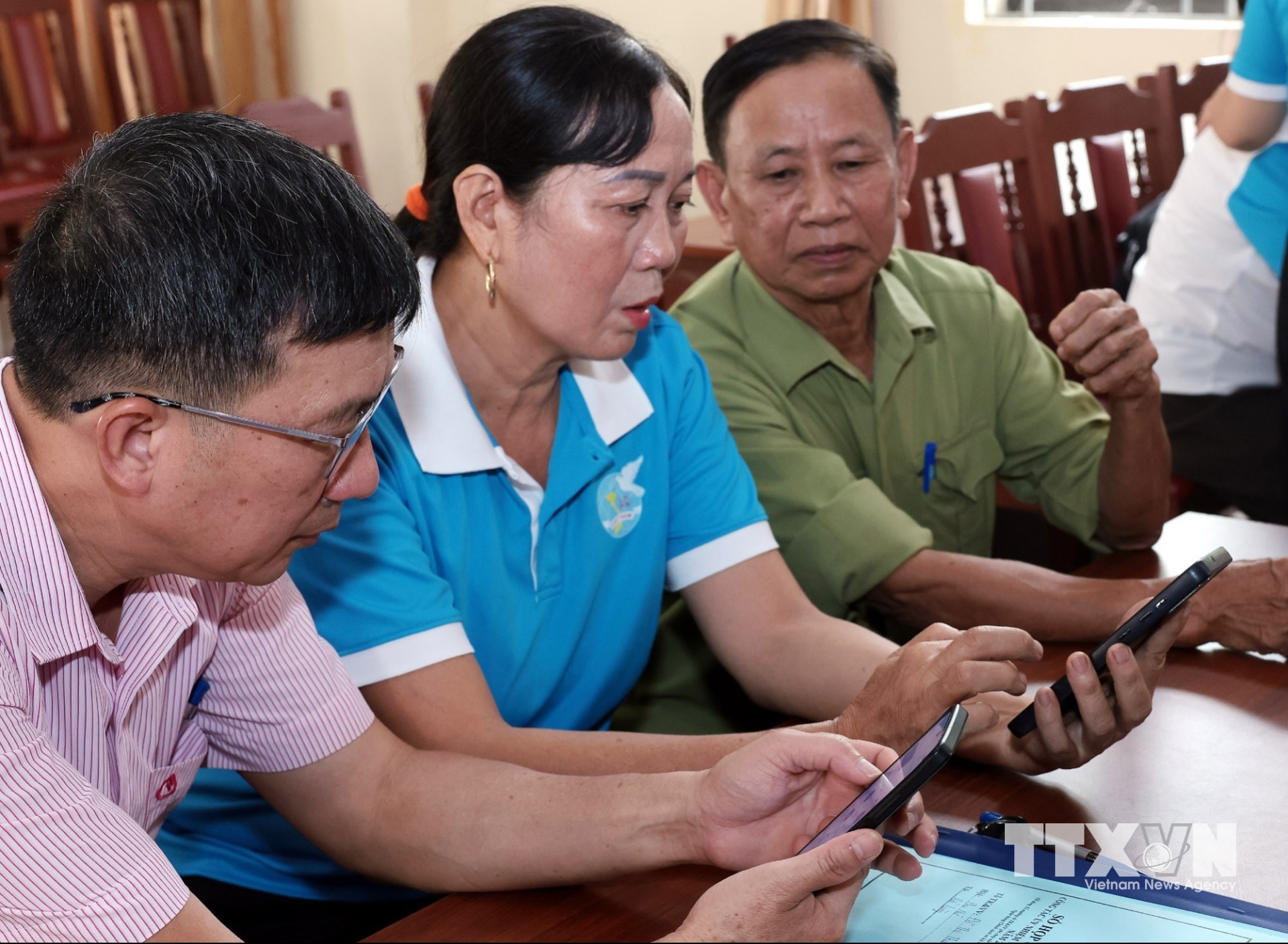 Cán bộ NHCSXH Lục Nam hướng dẫn Tổ trưởng tổ tiết kiệm vay vốn sử dụng qua ứng dụng VBSP SmartBanking. (Ảnh: Trần Việt/TTXVN)